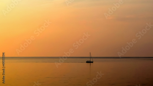 sunset on the Mediterranean sea in Cefalu, northern cost of Sicily. Italy. Amazing orange color of the sky and a boat navigating