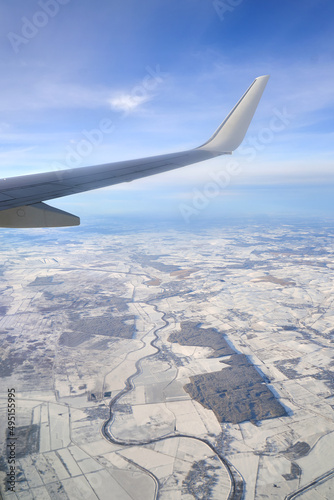 Obraz na płótnie Flying and traveling. View from airplane window on the wing during sunset. Plane over land in winter. w salonie