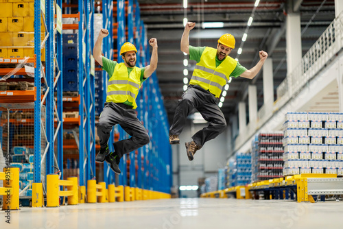Konstfotografi Two warehouse workers jumping and celebrating success.