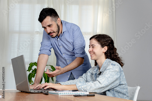 Trabajadores de oficina exitosos ríen mientras miran el ordenador. Trabajo de oficina. © Facundo
