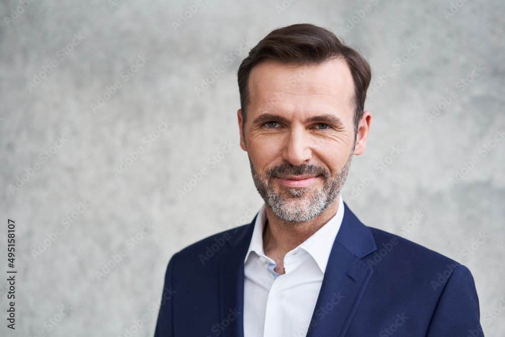 Close-up portrait of mid adult businessman smiling and looking at camera Close-up portrait of mid adult businessman smiling and looking at camera