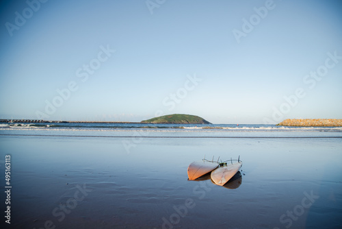 Two surfboards on the beach at sunset with Muttonbird Island in the distance. Coffs Harbour  Australia