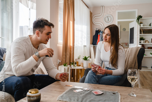 Two people man and woman young couple husband and wife brother and sister or boyfriend and girlfriend playing cards at home in bright day real people leisure games concept having fun copy space