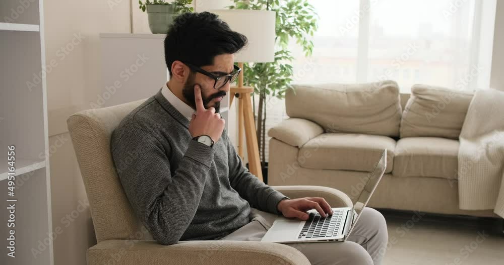Man working on laptop sitting on armchair at home Man working on laptop sitting on armchair at home