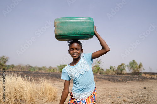 Fototapet Brave young African girl on her long and arduous walk home from the distant vill