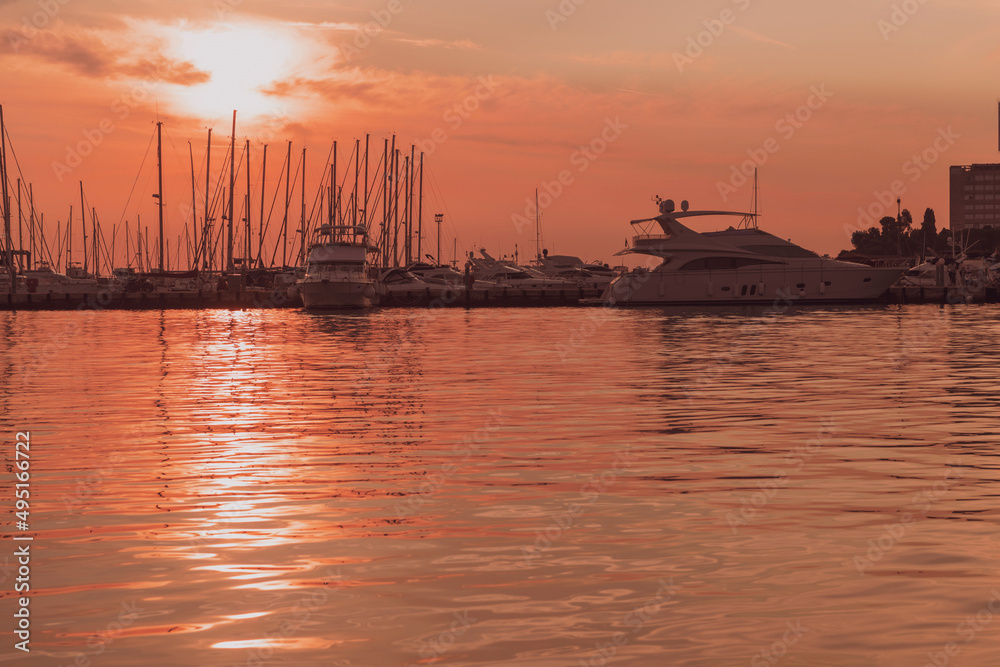 Sunrise on the seashore. In the silhouette of the ships in the harbor. Selective focus 