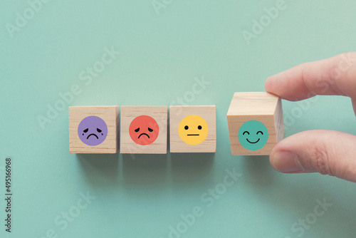 Hand choosing happy smile face wooden block, good feedback rating and positive customer review, mental health assessment, child wellness,world mental health day, think positive, compliment day concept photo