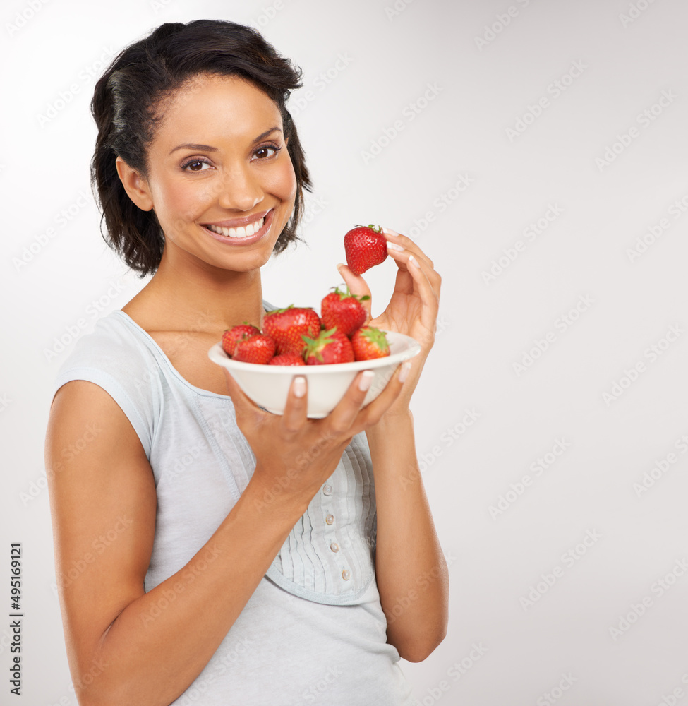 Sweet, juicy and absolutely delicious. Portrait of a young woman enjoying a bowl of strawberries. Sweet, juicy and absolutely delicious. Portrait of a young woman enjoying a bowl of strawberries.