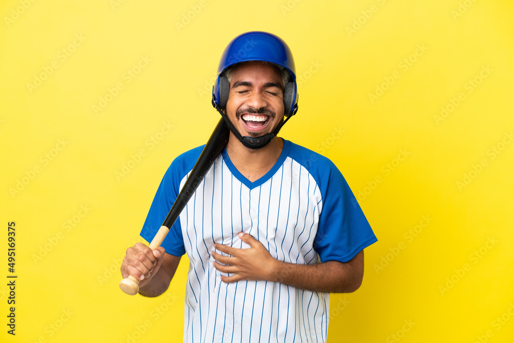 Young Colombian latin man playing baseball isolated on yellow background smiling a lot