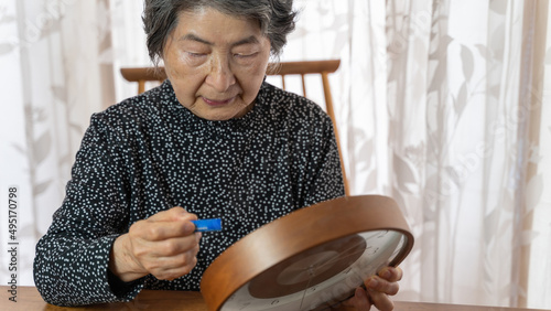 時計の電池を交換する黒い服を着た高齢者女性