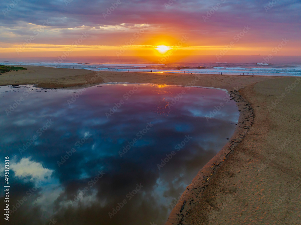 Sunrise reflections and clouds at the seaside with lagoon