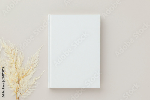 White book blank cover mockup on a beige background with dry flower, flat lay, mockup