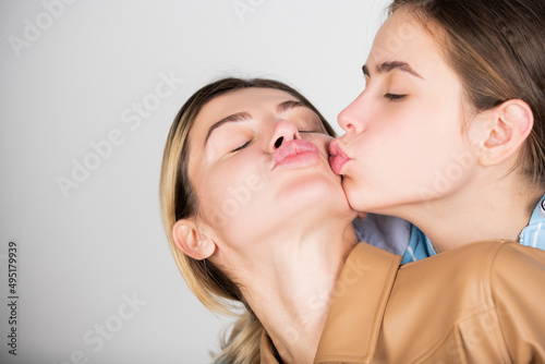 Portrait of young pretty models kissing. Two girls with beautiful eyes kissed, nice lips. Lesbians lgbt couple kiss. Perfect eyebrows and lashes. Visage and cosmetic advertising, perfect makeup.