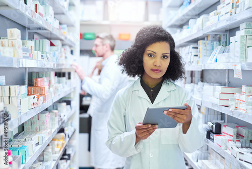 Its the smartest way to manage a modern pharmacy. Shot of a young woman using a digital tablet to do inventory in a pharmacy. photo