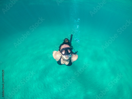 Girl diving into the ocean. Snorkel mask, turquoise water and bubbles. Fernando de Noronha archipelago, Brazil