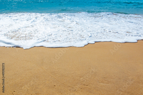 Sea Shore: Gentle waves reach the sand Sea Shore with Blue wave and white foamy summer background,