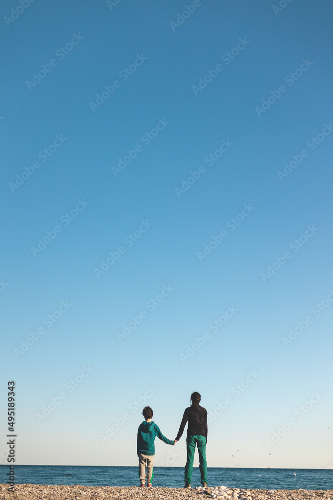a boy and mother look at the sea
