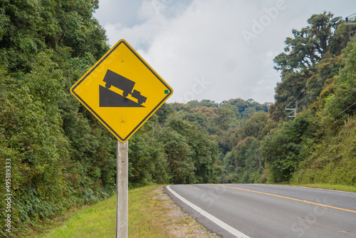 Warning downhill steep road sign in forest mountain. Transportation concept.