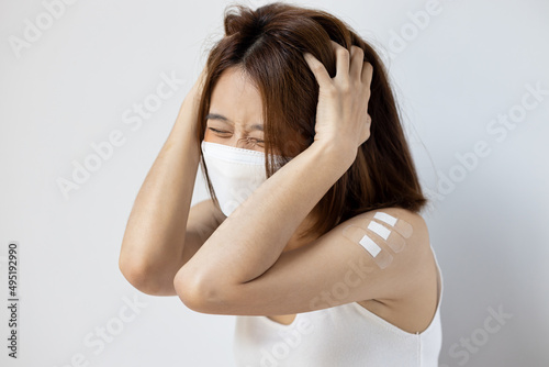 Concept image of fully vaccinated asian woman getting boosted with the first booster, experiencing headache, fever, adverse event side effect after vaccine booster shot