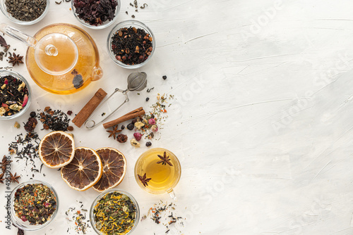 A set of different varieties of Chinese herbal and green tea in a glass dish and a kettle with hot tea on a green background. View from above. Space for text. Herbal treatment. Healthy lifestyle.