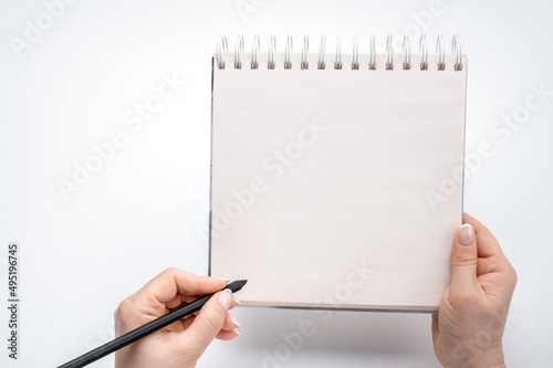 woman hands lefty writing in empty notebook at white desk. person holding pen over blank notebook on white background