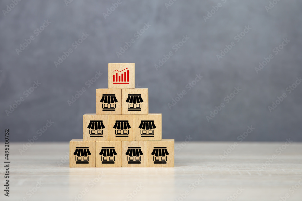 Close-up wooden block stack pyramid with graph and franchise business store icon for franchising to growth branch expansion and business banking loans. - obrazy, fototapety, plakaty 