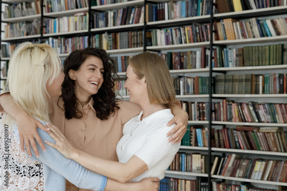 Three students girls, best friends meets in library hugging glad to see each other feel happy, look overjoyed, express love. Multi national friendship, good warm relations between schoolmates concept Three students girls, best friends meets in library hugging glad to see each other feel happy, look overjoyed, express love. Multi national friendship, good warm relations between schoolmates concept