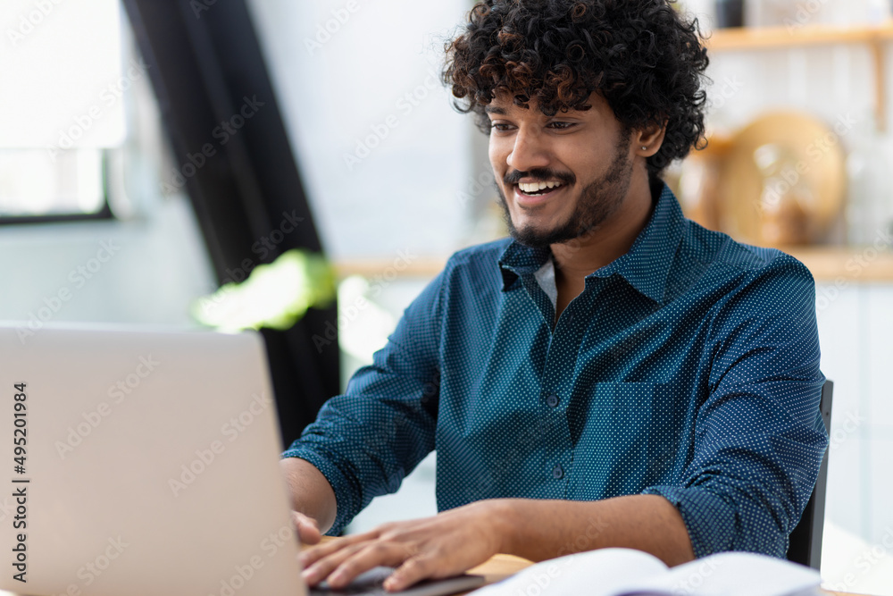 Smiling young Indian man freelancer using laptop computer typing working online coworking or modern office Asian student studying from home watching training courses Distance learning online education Smiling young Indian man freelancer using laptop computer typing working online coworking or modern office Asian student studying from home watching training courses Distance learning online education