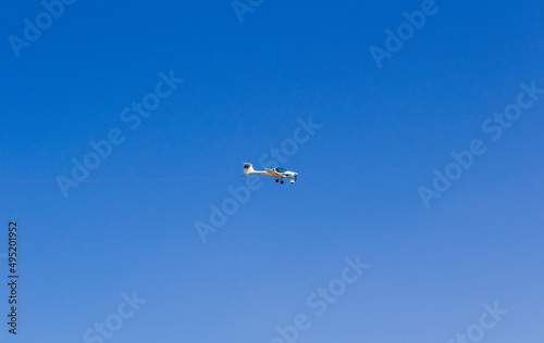 Ultra light, cessna plane from side with prolonge rope on blue sky. Sport, transportation background