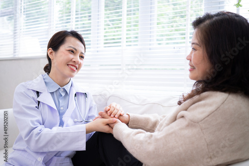 Asian female doctor examining an elderly woman at home