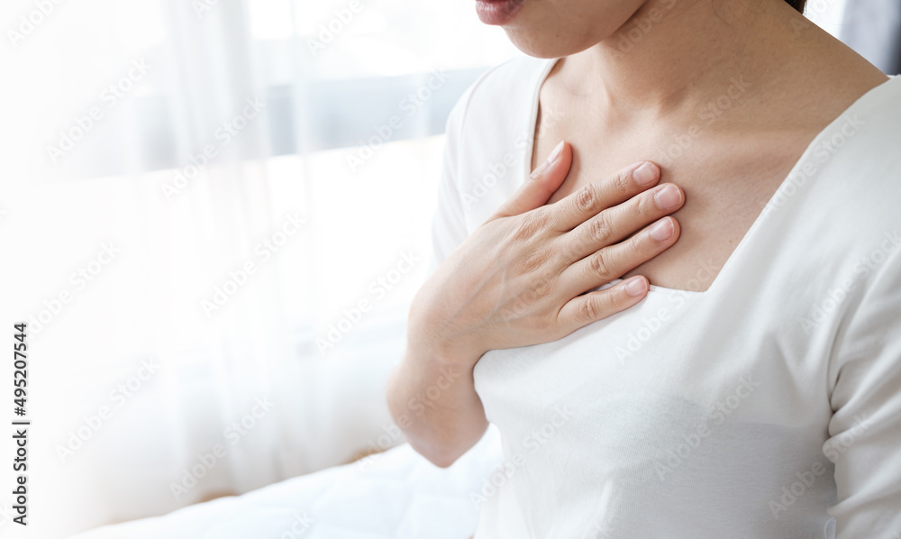 Young woman putting her hand on her chest. Having a pain in chest, Gastroesophageal Reflux