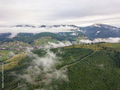 Green slopes of Ukrainian Carpathian mountains in summer. Cloudy morning, low clouds. Aerial drone view. © Sergey