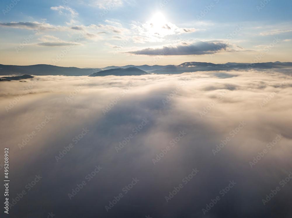 Flight over fog in Ukrainian Carpathians in summer. Mountains on the horizon. A thick layer of fog covers the mountains with a continuous carpet. Aerial drone view. Flight over fog in Ukrainian Carpathians in summer. Mountains on the horizon. A thick layer of fog covers the mountains with a continuous carpet. Aerial drone view.