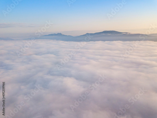 Flight over fog in Ukrainian Carpathians in summer. Mountains on the horizon. Aerial drone view. © Sergey