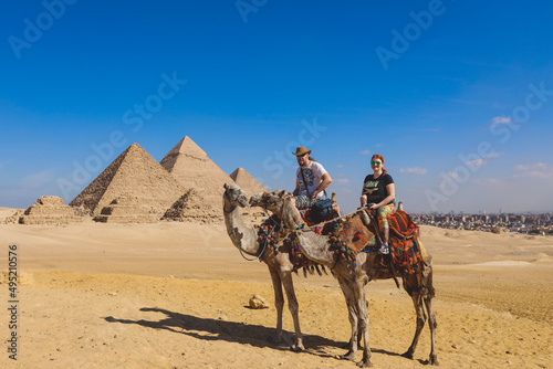 White Man and Woman Tourists are Riding on the Camels with the Great Pyramid on Background in Giza  Egypt