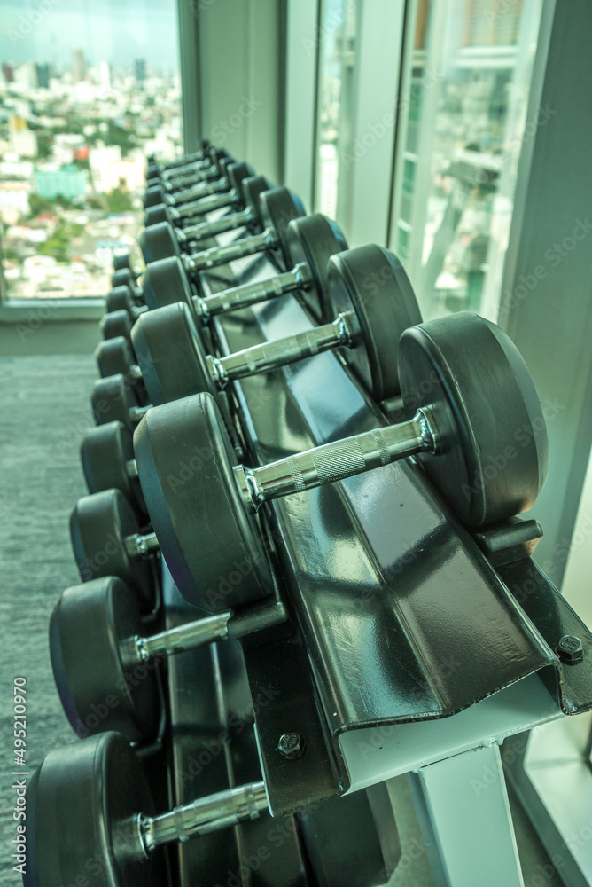 Rubber Dumbbells on shelf in modern fitness gym. Sport and healthcare concept.	