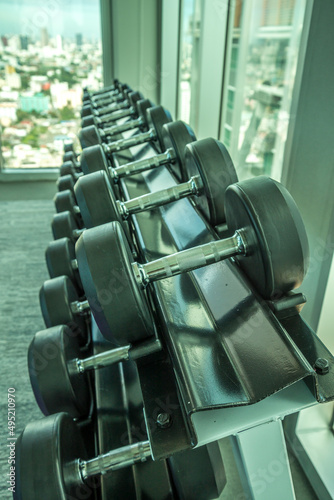 Rubber Dumbbells on shelf in modern fitness gym. Sport and healthcare concept. 