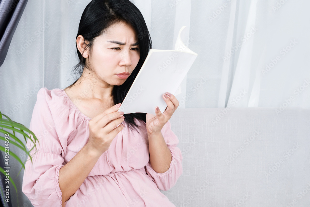 Asian woman reading book too close to the eye having problem with shortsighted, vision problem concept Asian woman reading book too close to the eye having problem with shortsighted, vision problem concept
