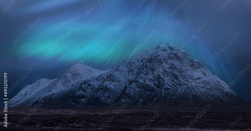 Majestic vibrant Northern Lights Aurora composite image over landscape of snowcapped mountains in Scottish Highlands