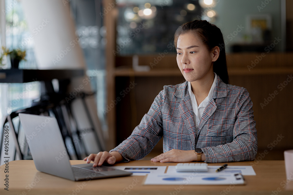Beautiful Asian young woman looking at information on a laptop, concept image of Asian business woman working smart, modern female executive, startup business woman, business leader woman. Beautiful Asian young woman looking at information on a laptop, concept image of Asian business woman working smart, modern female executive, startup business woman, business leader woman.