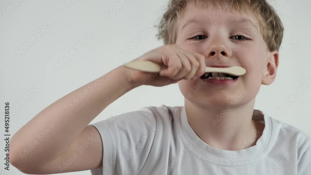 Young little boy brushing his teeth using bamboo tooth brush for cleaning teeth on white background. Learning dental education. Young little boy brushing his teeth using bamboo tooth brush for cleaning teeth on white background. Learning dental education.