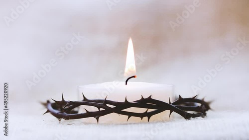 Crown of thorns symbolizing the suffering cross, death and resurrection of Jesus Christ and brightly shining candle background photo