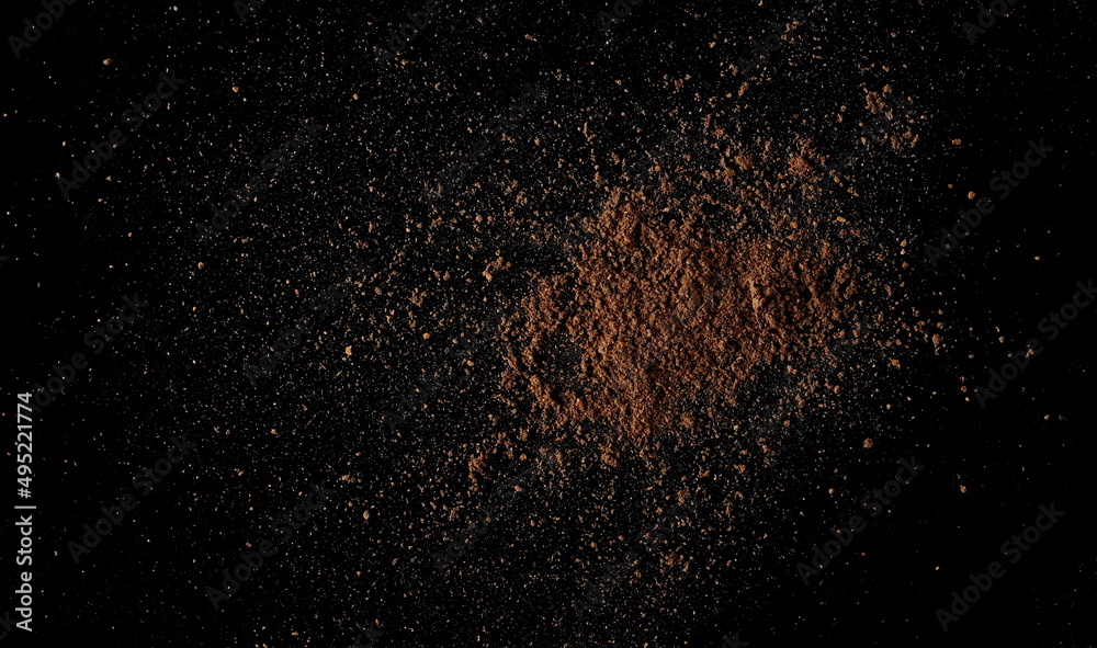 Ground, milled nutmeg powder isolated on black, top view