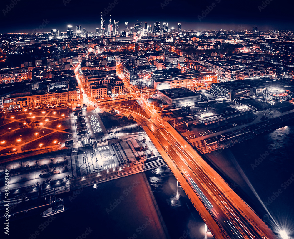 Beautiful panoramic aerial drone skyline view of the center of night Warsaw with skyscrapers in the background with the Swietokrzyski suspension bridge - the lights of the big city by night, Poland