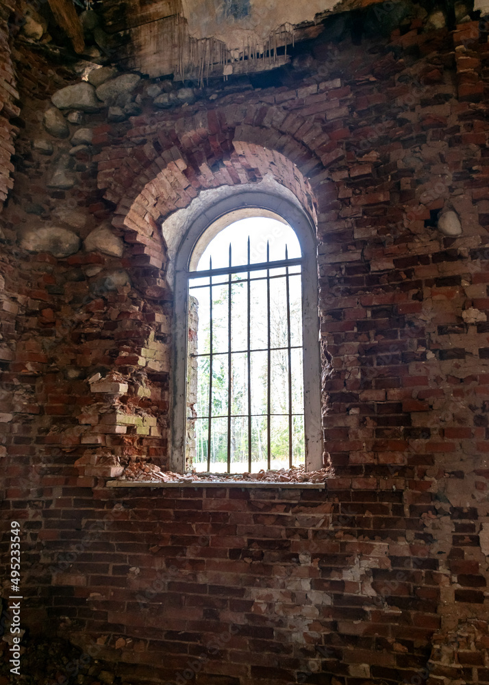 old arched windows in an abandoned church, iron grilles in front of the windows, crumbling window sills and window sills