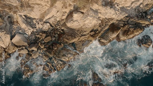 Aerial top down view of rocky coastline. sunset light and big waves