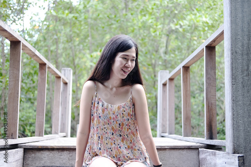 Free Download Pretty Asain girl is smiling and sitting on wooden bridge in the tropical mangrove forest at Thailand - GFXLoad