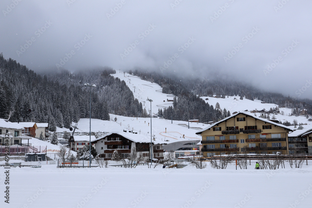 View to the foggy, snowy Landscape, Skiing Slope and the Houses of Churwalden, Switzerland in Wintertime