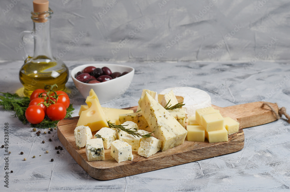 Board with assortment of delicious cheese on board. Wooden background, copy space.