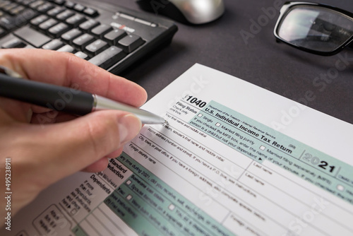  a woman's hand filling out a tax form 1040